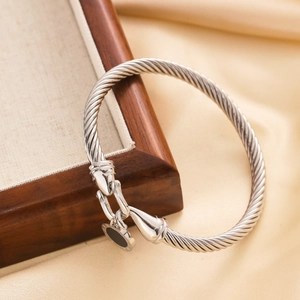 Detailed view of silver twisted cable bracelet with a black enamel round charm detail