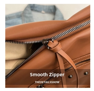 Macro shot of silver metal zipper and brown leather texture on a commuter tote bag