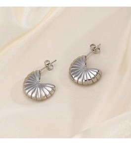 Macro detail of silver geometric semi-circle earrings on elegant silk fabric background