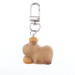 Detailed close-up of a cartoon capybara keychain with orange fruit decor and silver metal clasp