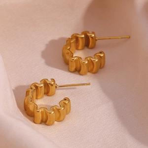 Détails macro des boucles d'oreilles créoles C ondulées en acier plaqué or 18 carats