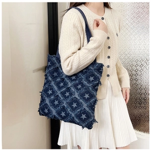 Close-up of star pattern denim bucket bag with raw edges worn by model