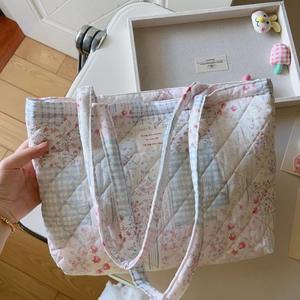 Nahaufnahme von gestepptem Baumwollstoff mit Blumen und Karos auf einer Tragetasche
