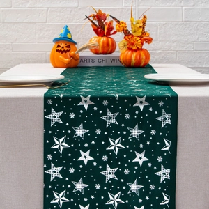 Deep green velvet table runner with white star and snowflake patterns on a dining table