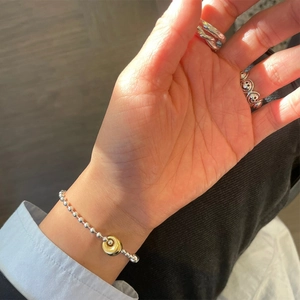 Detail of 925 silver beaded bracelet with gold charm and vintage smiley face ring