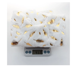 Detailed view of white plush Christmas tree skirt with gold feathers weighing 411.5g