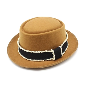 Detail of camel wool boater hat with black ribbon and delicate white bead embellishments