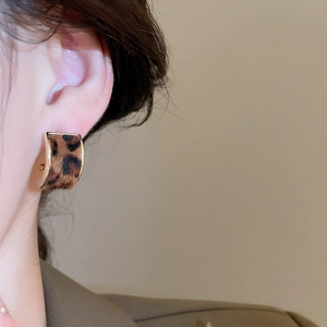 Close-up of vintage leopard print C-shaped earring with elegant gold trim on model