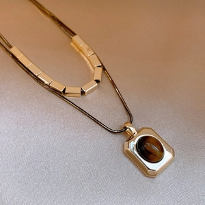 Detailed macro view of 18k gold plated double layer necklace with tiger eye stone pendant