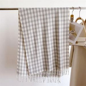 Detailed close-up of a grey plaid scarf with soft fringe texture hanging on a metal rack