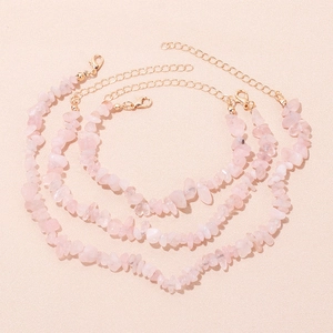 Macro view of three pink quartz stone bracelets with gold clasps on sand background