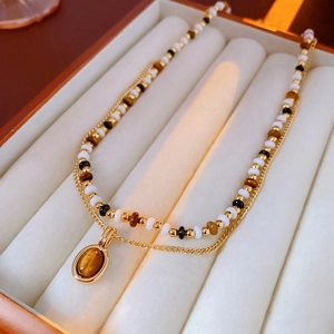 Double-layered gold plated necklace with oval tiger eye stone on cream velvet tray