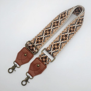 Detail of adjustable ethnic style bag strap with vintage jacquard pattern and bronze hooks