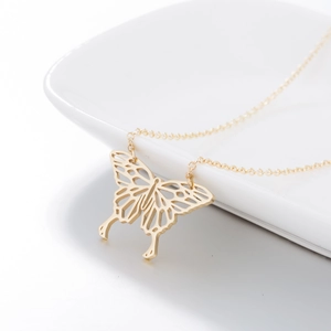 Detailed view of a gold hollow butterfly pendant on a delicate cross chain necklace
