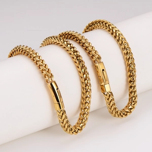 Polished gold woven chain bracelets with snap clasp displayed on a white stand
