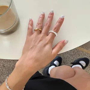 Close-up of minimalist gold open ring and silver beaded bracelet on hand in cozy setting