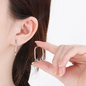 Close-up of a silver rectangular stainless steel earring worn on a female ear