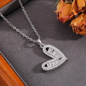 Dettaglio della collana a cuore argento con diamanti baguette su superficie grigia