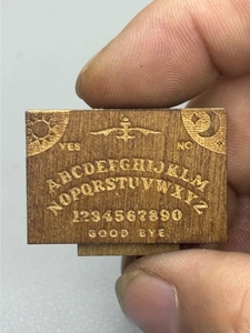 Macro shot of miniature wooden Ouija board with detailed laser engraved letters and numbers