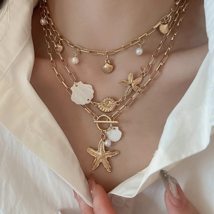Detail of layered gold shell and starfish necklace showing fine ocean-themed charms