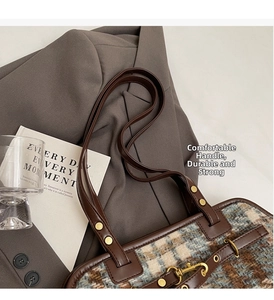 Close-up of vintage plaid bucket bag with leather handles and gold metal rivets