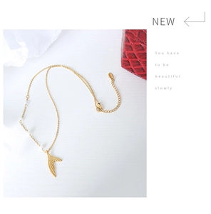 Detailed shot of gold-plated mermaid tail pendant necklace featuring small white pearls