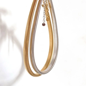 Close-up of flexible snake bone chain necklaces in gold and silver metallic finishes