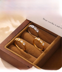 Detailed view of three 18K gold and silver plated rings with zirconia in a wooden box