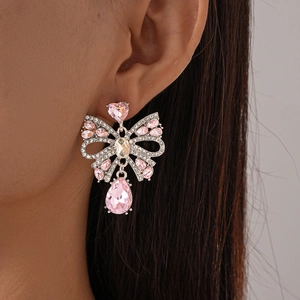 Gros plan de boucles d'oreilles nœud en cristal rose avec goutte sur l'oreille du mannequin