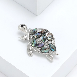 Vintage sea turtle brooch with colorful abalone shell inlay and white crystals on white stone
