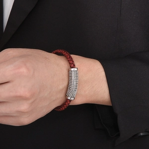 Detail of red braided leather bracelet with silver magnetic clasp on man's wrist