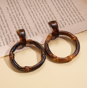 Detail of dark brown resin bamboo hoop earrings with amber tortoise shell studs