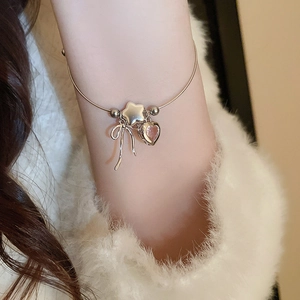 Silver bangle with pink heart zircon, star and bow charms on a soft knit background