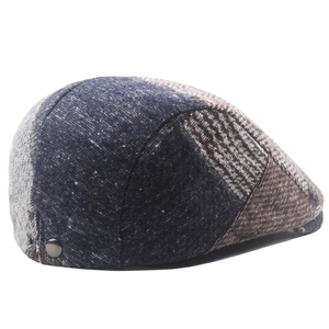 Detail of multi-color patchwork newsboy cap featuring wool blend fabric and side metal button