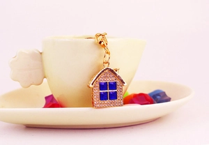 Detail of gold house keychain with rhinestones hanging on a soft pastel ceramic cup