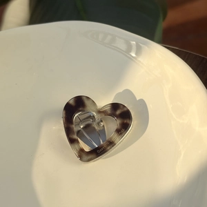 Detailed close-up of a heart-shaped acetate hair clip with tortoiseshell pattern on ceramic