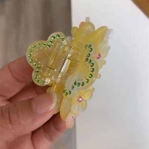 Macro shot of yellow acetate flower hair claw clip with colorful rhinestone embellishments
