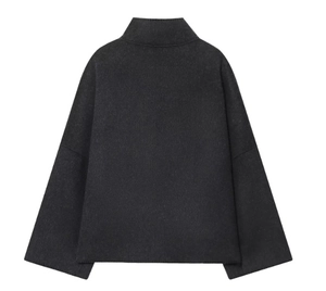 Macro view of dark grey textured jacket showing high collar and seamless shoulder seams