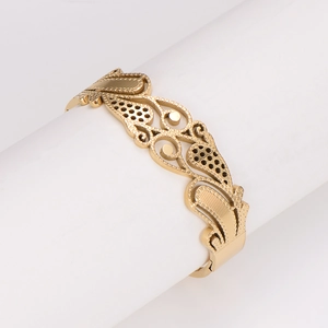 Dettaglio macro del bracciale rigido in acciaio inossidabile dorato con motivo a spiga