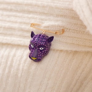 Détail d'une broche tête de léopard violette avec épingle dorée sur maille blanche