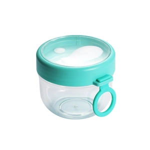 Portable oatmeal yogurt cup with green lid and spoon on white background