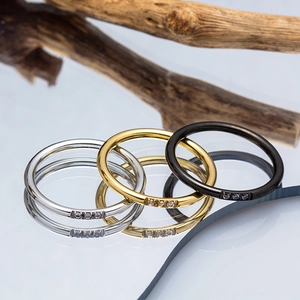 Three minimalist titanium steel rings in gold, silver, and black with three inset diamonds