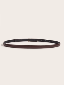 Detail of slim dark brown leather belt with fine texture and minimalist pin buckle design