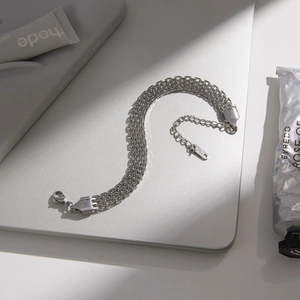 Minimalist silver multi-layer stainless steel bracelet displayed on a metal surface