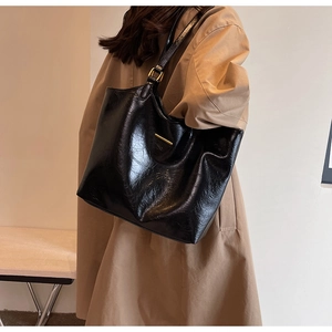 Side view of soft black leather tote bag with metallic buckle detail on model