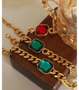 Close-up of gold-plated chunky Cuban chains with red, green, and blue square crystals