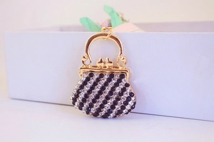 Close-up of golden alloy purse keychain with black and white rhinestones and bird clasp