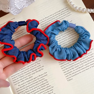 Detail of denim scrunchies with red wavy trim and pearl accents on vintage book