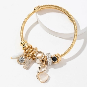 Golden woven bracelet with swan charm, heart cat eye stone and rhinestone beads on white base