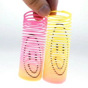 Close-up of two mini gradient rainbow spring toys with black smiley faces for children